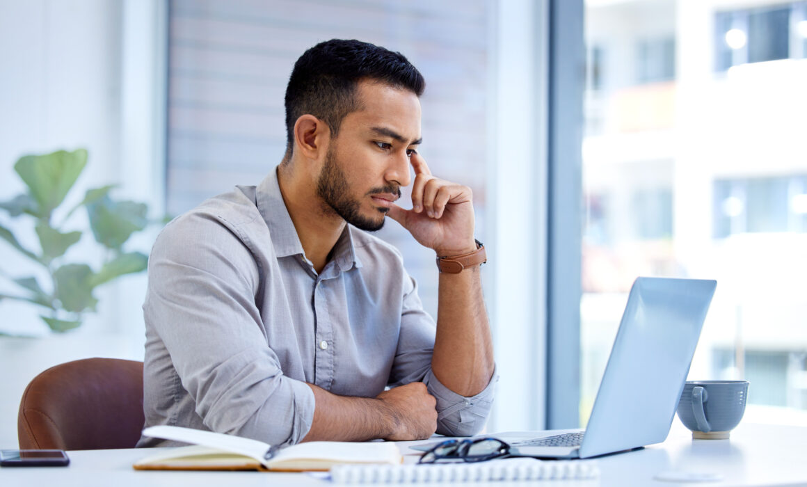 Shot of a young businessman working on a laptop in an office